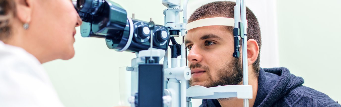 Uomo giovane sottoposto a visita oculistica con lampada a fessura