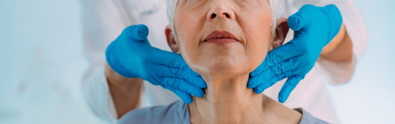Medico controlla durante una visita endocrinologa una paziente anziana palpando la tiroide per controllare le ghiandole