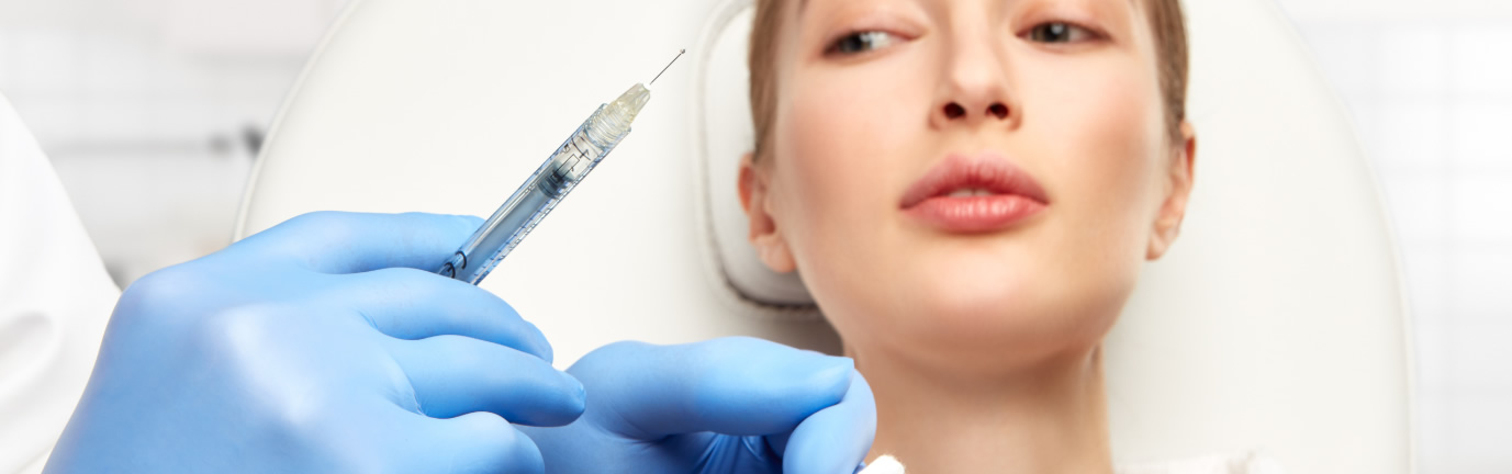Medico con siringa che si prepara ad effettuare il filler alle labbra di una paziente